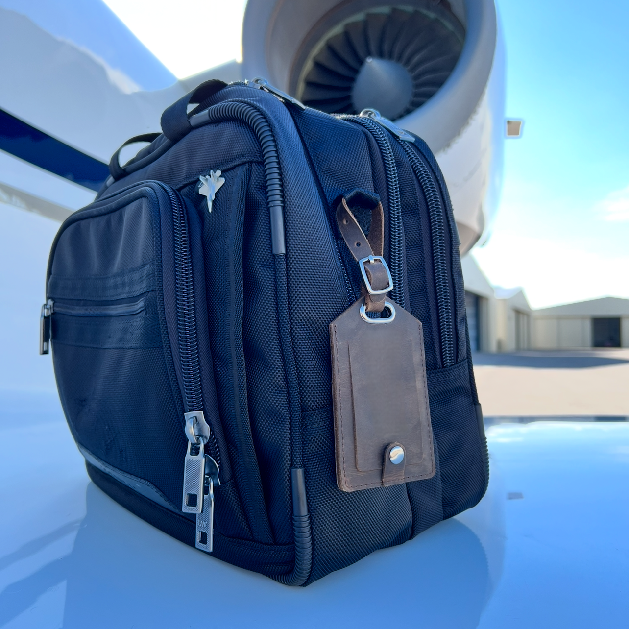 Leather AirTag luggage tag attached to flight bag on the wing